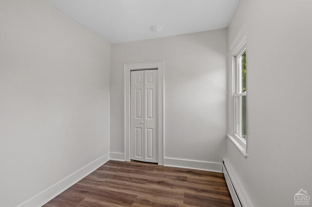 spare room featuring baseboard heating and dark hardwood / wood-style floors