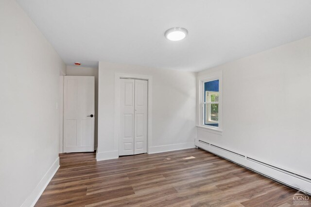 unfurnished bedroom featuring a closet, dark wood-type flooring, and a baseboard radiator