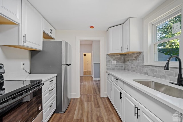 kitchen with white cabinets, stove, light hardwood / wood-style flooring, and sink