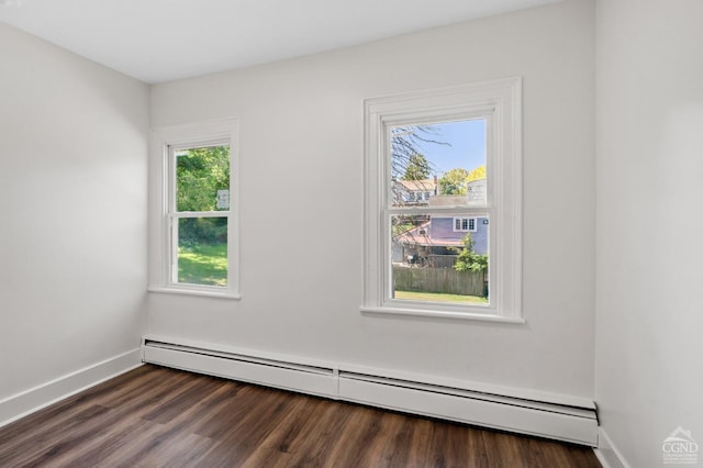 spare room with a wealth of natural light, dark hardwood / wood-style flooring, and a baseboard radiator