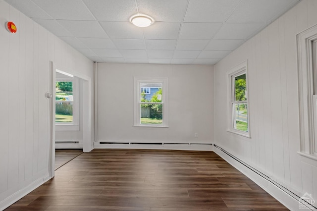 spare room featuring dark hardwood / wood-style flooring, baseboard heating, and plenty of natural light