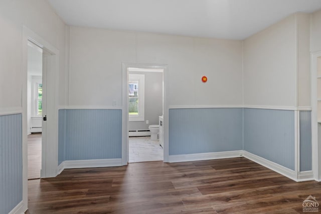 empty room featuring a baseboard radiator and dark hardwood / wood-style floors