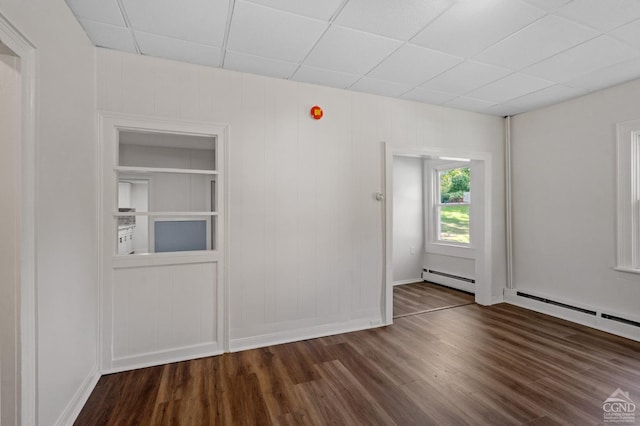 spare room featuring a paneled ceiling, dark wood-type flooring, and a baseboard radiator