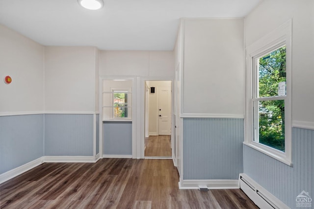 spare room with baseboard heating and dark wood-type flooring