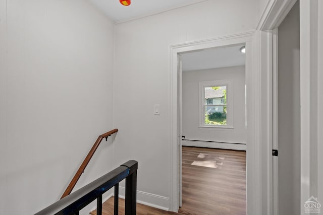 stairs featuring hardwood / wood-style floors and a baseboard radiator