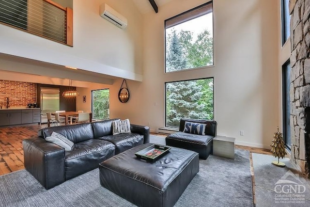 living room featuring a wall unit AC, plenty of natural light, a towering ceiling, and hardwood / wood-style flooring