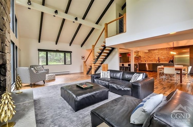 living room featuring brick wall, baseboard heating, beam ceiling, hardwood / wood-style flooring, and high vaulted ceiling