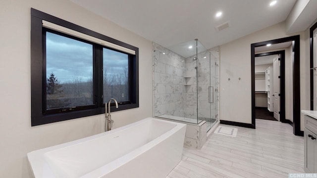 full bathroom with a stall shower, visible vents, a spacious closet, a freestanding bath, and vanity