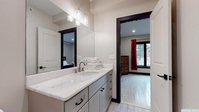 bathroom featuring wood finished floors, vanity, and ensuite bathroom