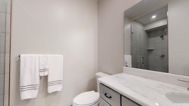 bathroom with toilet, a shower stall, and vanity