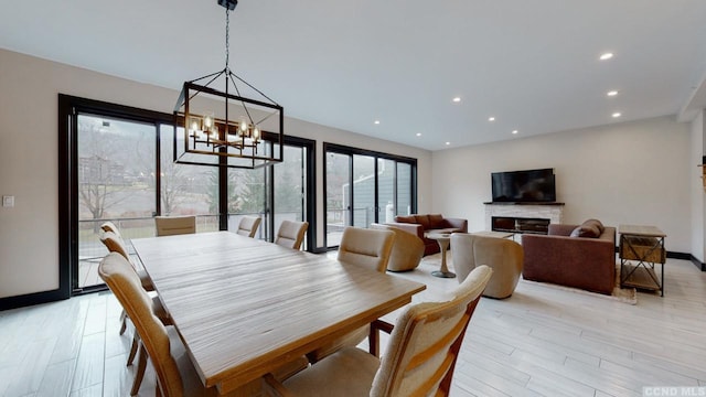 dining room featuring light wood-style floors, recessed lighting, a notable chandelier, and a fireplace