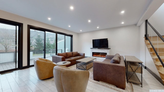 living area with recessed lighting, stairs, and a glass covered fireplace