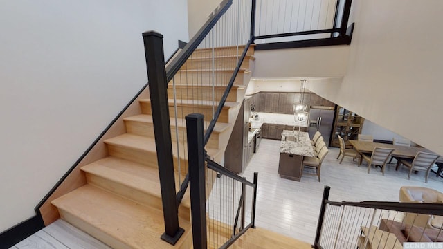 staircase featuring a high ceiling and wood finished floors