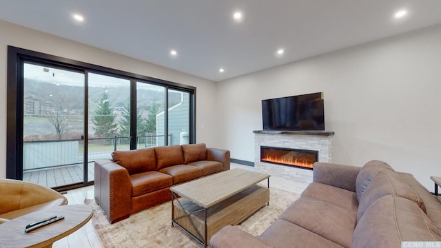 living room with light wood finished floors, a glass covered fireplace, and recessed lighting