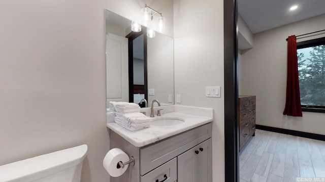 bathroom with wood finished floors, vanity, and toilet