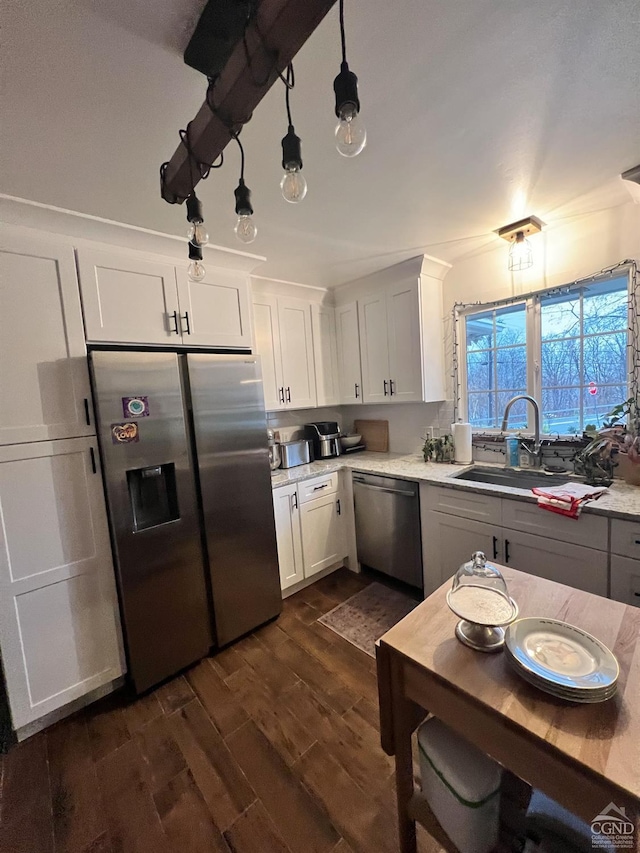 kitchen featuring pendant lighting, sink, white cabinets, and stainless steel appliances