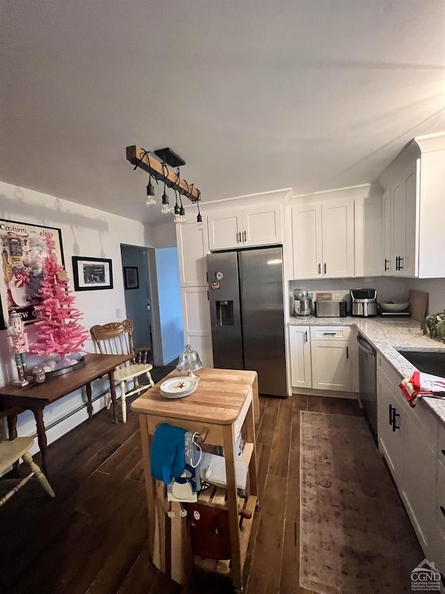 kitchen with light stone counters, white cabinetry, dark wood-type flooring, and appliances with stainless steel finishes