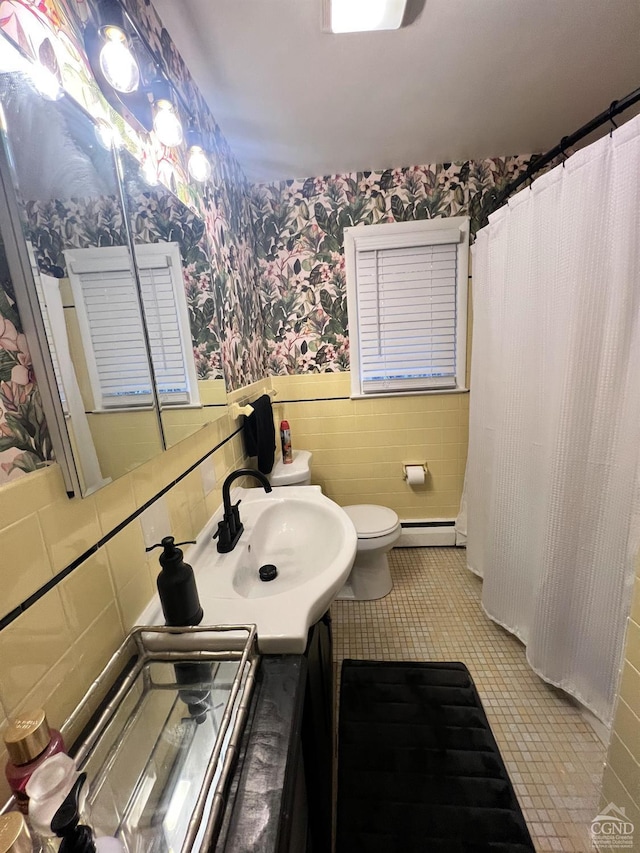 bathroom with vanity, a baseboard heating unit, tile patterned flooring, toilet, and tile walls