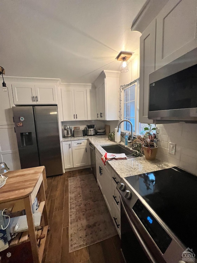 kitchen featuring sink, stainless steel appliances, light stone counters, decorative backsplash, and white cabinets