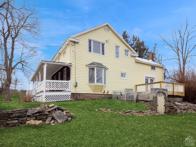 rear view of property with a lawn and a wooden deck