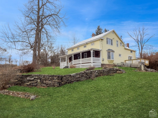 rear view of property with a sunroom and a yard