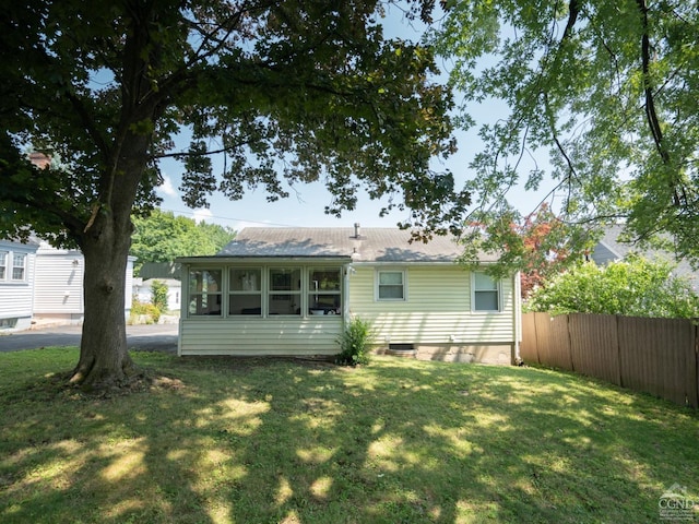 rear view of property with a lawn, roof with shingles, and fence