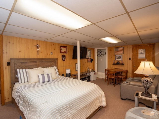 bedroom with wooden walls, a paneled ceiling, and carpet floors