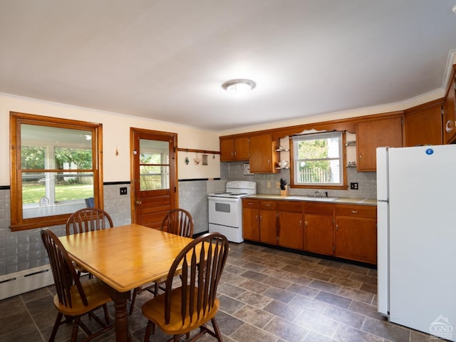 kitchen featuring white appliances, tile walls, a healthy amount of sunlight, and sink