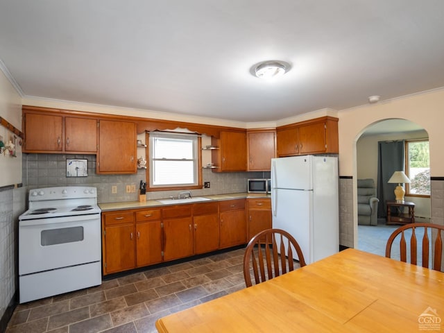 kitchen with a sink, open shelves, white appliances, arched walkways, and light countertops