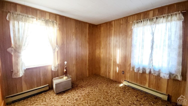 spare room featuring a baseboard radiator, carpet flooring, and wooden walls