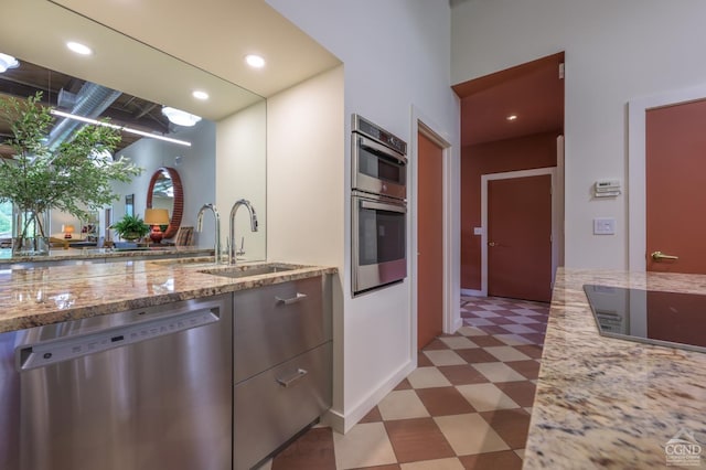 kitchen featuring light stone counters, sink, and stainless steel appliances