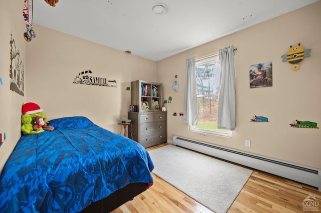 bedroom featuring hardwood / wood-style flooring and a baseboard heating unit