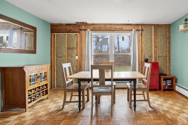 dining room with wooden walls, light parquet flooring, and a baseboard radiator