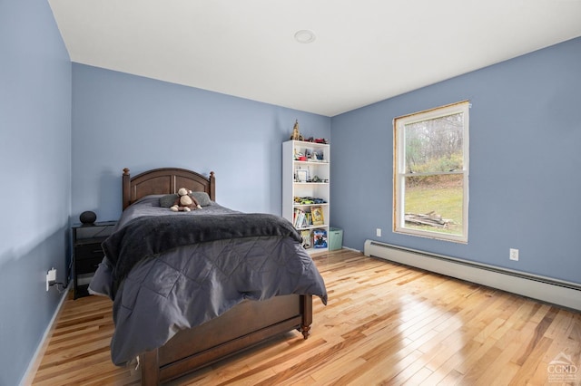 bedroom with hardwood / wood-style floors and a baseboard radiator