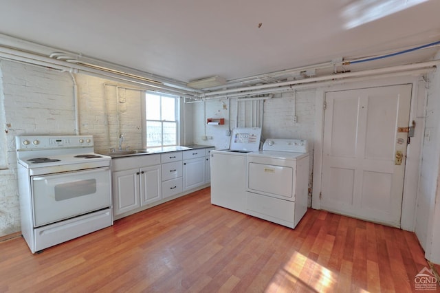 laundry area featuring washer and clothes dryer, light wood-type flooring, and sink