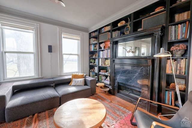 living area with crown molding, hardwood / wood-style floors, and a high end fireplace