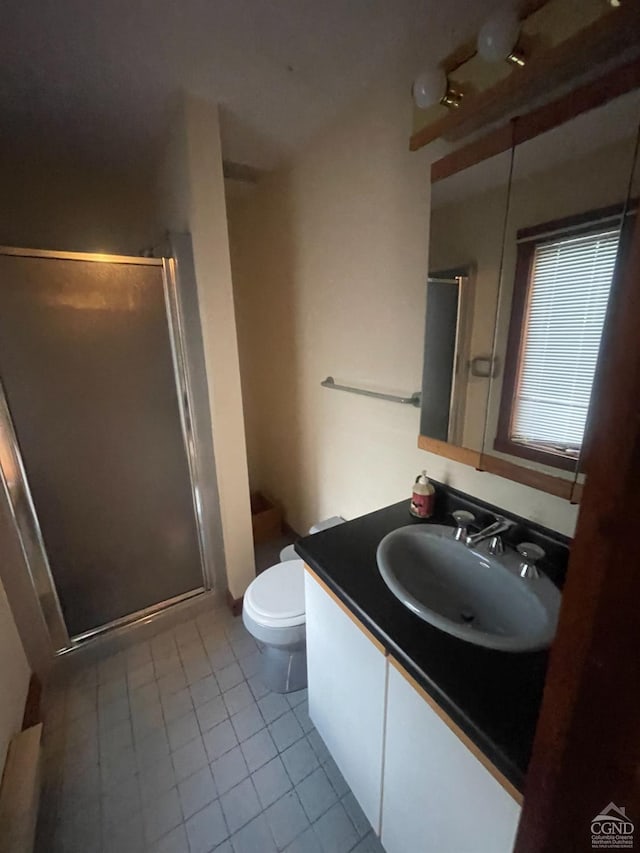 bathroom featuring tile patterned flooring, vanity, an enclosed shower, and toilet