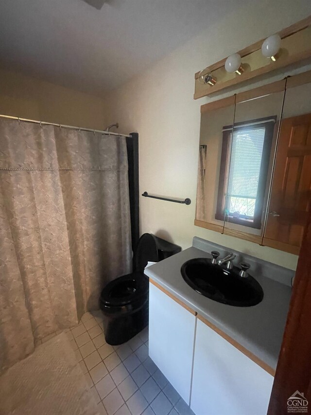 bathroom featuring tile patterned flooring, vanity, toilet, and walk in shower