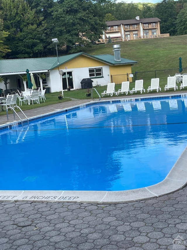 view of pool with a lawn and a grill