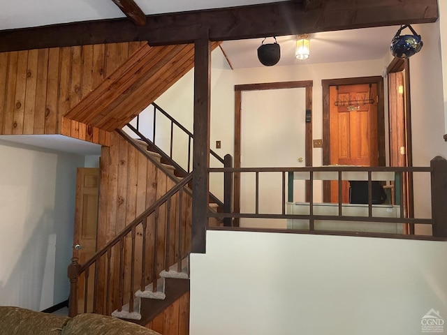 stairway with wood walls and beam ceiling