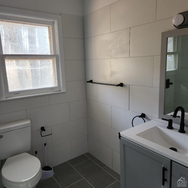 bathroom featuring tile patterned floors, vanity, tile walls, and toilet