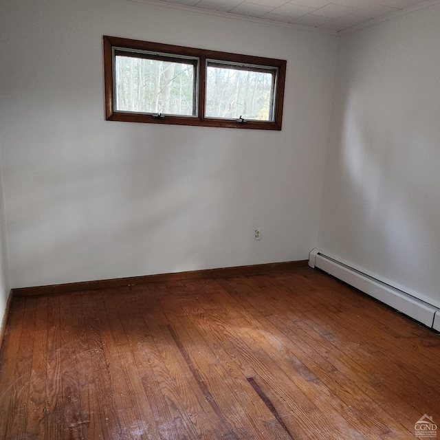 empty room featuring wood-type flooring, a baseboard radiator, and plenty of natural light