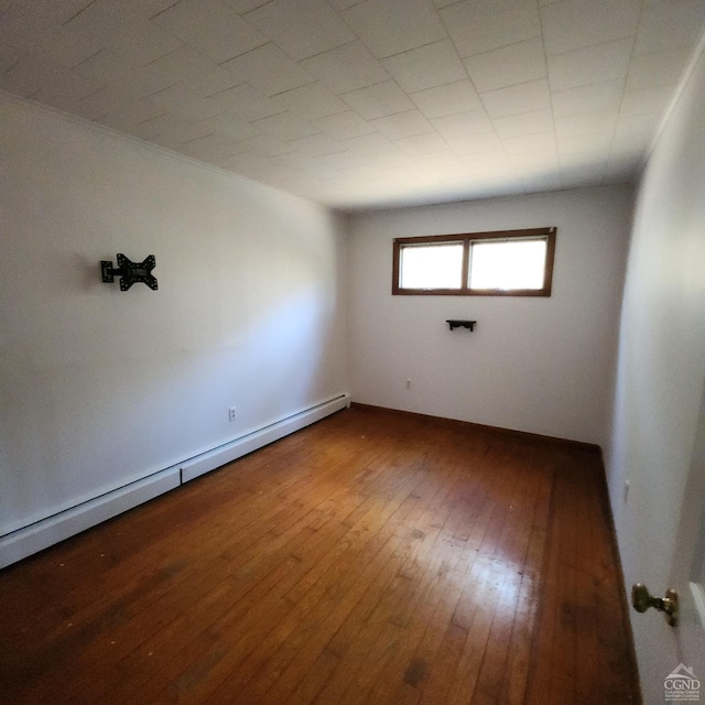 unfurnished room with hardwood / wood-style flooring and a baseboard heating unit