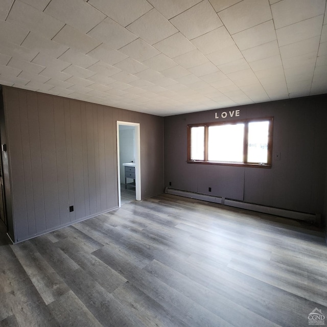 unfurnished room with a baseboard radiator and hardwood / wood-style flooring