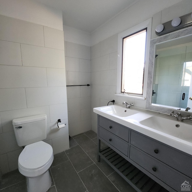 bathroom with toilet, vanity, tile patterned floors, and tile walls