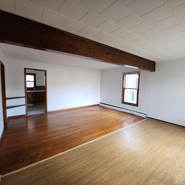 spare room with sink, beamed ceiling, light wood-type flooring, and a baseboard heating unit