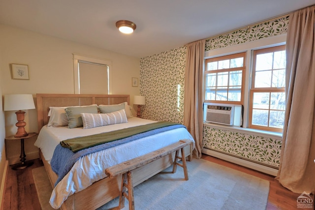 bedroom with baseboard heating, hardwood / wood-style floors, and cooling unit