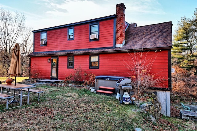 rear view of house featuring cooling unit and a hot tub