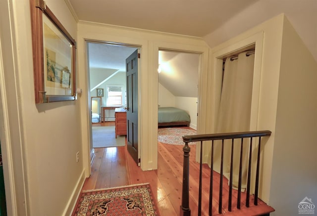 corridor with lofted ceiling, light wood-type flooring, and ornamental molding