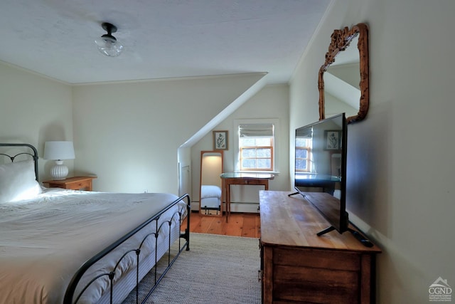 bedroom featuring ornamental molding, baseboard heating, and light hardwood / wood-style flooring